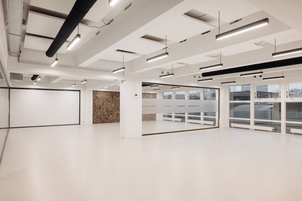 Moderne, leegstaande kantoorruimte aan de Generaal Vetterstraat met witte vloeren, glazen wanden en industriële plafondverlichting.